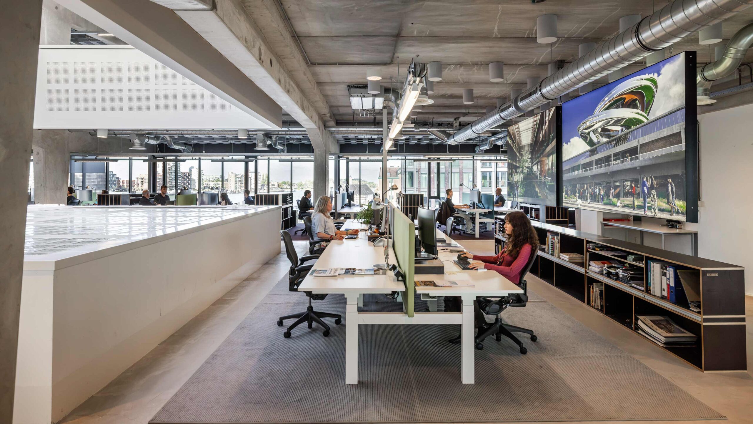 Modern open kantoor van EGM architecten met medewerkers aan bureaus, computers, grote ramen